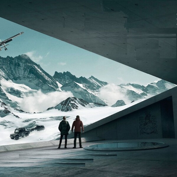 Photo of 007 Elements in Solden Austria. Image shows two people looking out onto a snowy mountain range with a Land Rover and plane in the distance