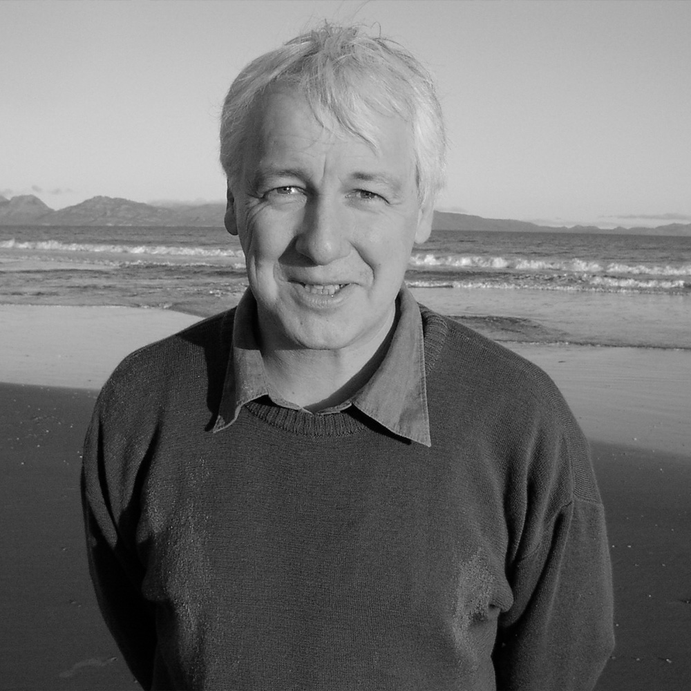 Black and white photograph of author Nicholas Shakespeare, a middle aged white man pictured in front of the sea.