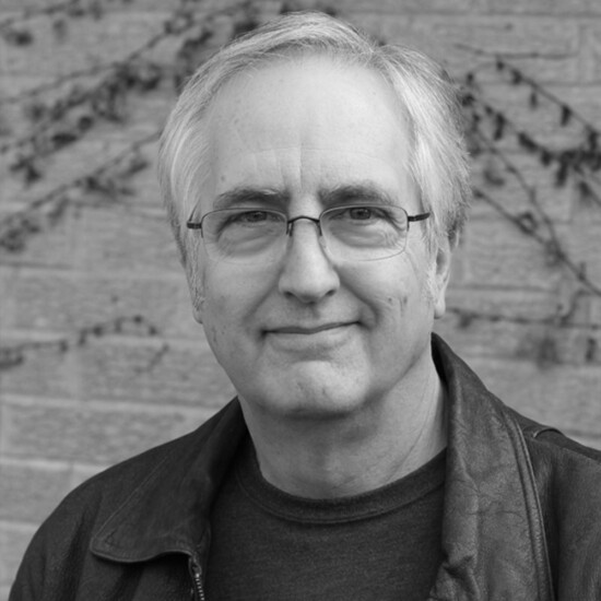 Black and white photograph of author Raymond Benson, a middle aged white man wearing glasses.