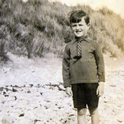 Black and white photograph of Ian Fleming as a boy on a pebble beach, aged approximately 5.